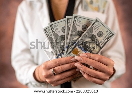 Cropped photo of a woman holding US dollar money in her hands on the background of her body. isolated on plain background. budget planning. the concept of profit