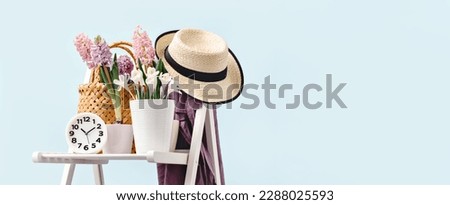 Clock and Several spring pink hyacinth flower plants potted at home on garden chair. Hat and apron. Flowerhead in bloom. Spring schedule or opening hours. Home Garden calendar banner