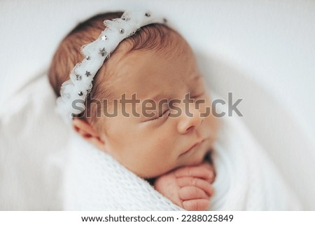 Newborn baby girl photographed in studio, on white background. Stylized and wrapped in bucket. Closeup portrait. Royalty-Free Stock Photo #2288025849