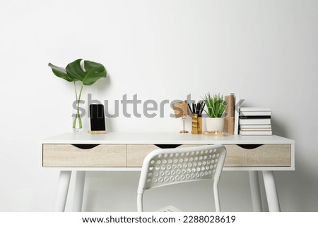 Comfortable workplace with white desk near wall Royalty-Free Stock Photo #2288028619