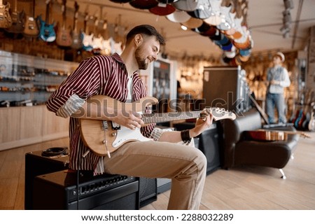 Man enjoying sound while playing guitar connected to amplifier Royalty-Free Stock Photo #2288032289