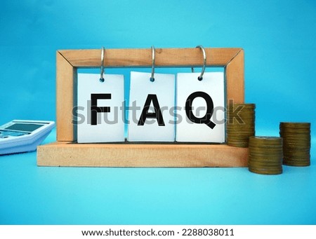 FAQ. wooden cubes. Writing on paper hangs on a wooden block. stack with coins. Selective focus on FAQ 