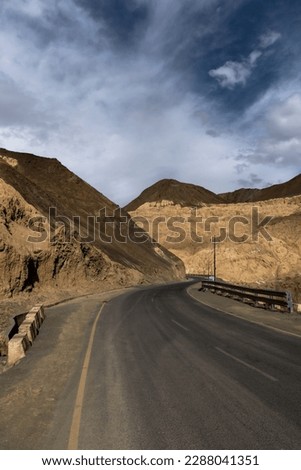 Curvy metal road winds through stunning Moonland Mountains in Ladakh near Lamayuru, offering breathtaking views.