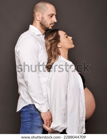 Photo of a beautiful couple of a man and pregnant woman smiling happily hugging together