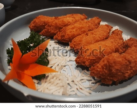 Tasty and delicious Ebi furai fried prawns with celery and carrot garnish on a gray plate