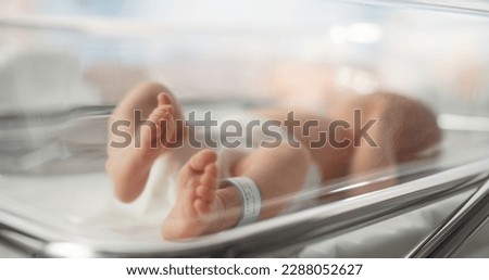 Cute Little Caucasian Newborn Baby Lying in Bassinet in a Maternity Hospital. Portrait of a Tiny Playful and Energetic Child with a Name ID Tag on the Leg. Healthcare, Pregnancy and Motherhood Concept Royalty-Free Stock Photo #2288052627