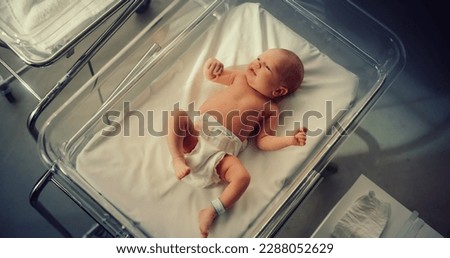 Adorable Small Caucasian Newborn Child Lying in Hospital Bed in a Nursery Clinic. Little Playful and Healthy Baby. Medical Health Care, Maternity and Parenthood Concept. High Angle Close Up Portrait Royalty-Free Stock Photo #2288052629