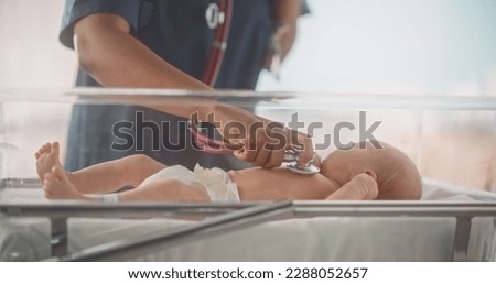 Happy Professional Nurse Providing Around-the-Clock Care to a Recovered Preterm Baby in Neonatal Intensive Care Unit. African Female Doctor Checking Up on a Child, Using Stethoscope in Nursery Clinic Royalty-Free Stock Photo #2288052657