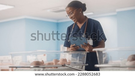 Young Nurse Using Tablet Computer Checking Up on a Newborn Baby in Maternity Ward Facility. Healthy Infant Lying in a Nursery Clinic, Waiting for Mother to Recover After Childbirth Royalty-Free Stock Photo #2288052683