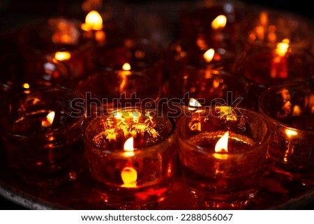 Close-up photo of a lot of red candles in glasses burning in a Chinese Taoist shrine at night. The flickering flames of the candles create a sacred atmosphere, inspiring hope and belief Royalty-Free Stock Photo #2288056067