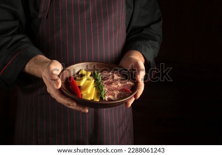 The waiter holds a plate of sliced ​​ham and cheese in his hands. Dark space for recipe or menu