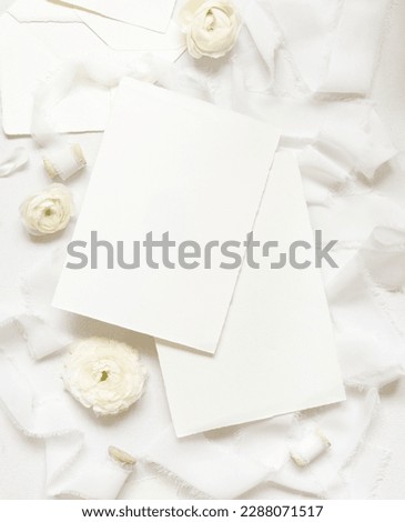 Blank cards near cream roses and white silk ribbons top view,  wedding mockup. Romantic scene with vertical cards and pastel flowers flat lay. Valentines, Spring or Mothers day concept