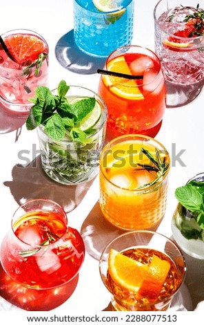 Summer cocktails drinks set. Assortment of multicolored strong and low alcoholic beverages for cocktail party. White background, hard light, shadows pattern, top view Royalty-Free Stock Photo #2288077513