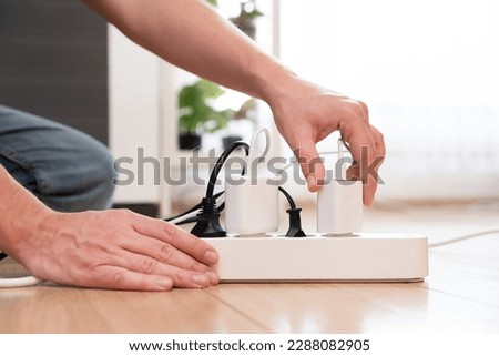 Hand holding electric plug, Multiple socket with connected plugs, energy efficiency Royalty-Free Stock Photo #2288082905
