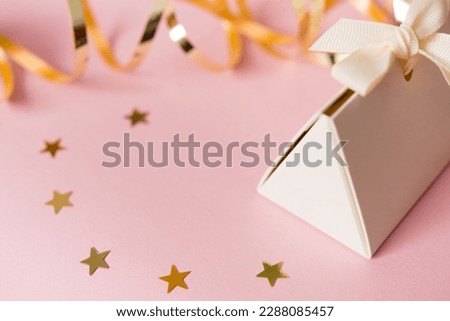 Festive pink background with a gift and golden gift ribbon. Happy mother's day, women's day or birthday in pastel colors. Mockup. Copy space	