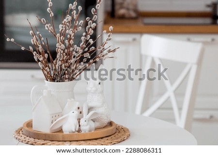 A bouquet of Willow twigs in a bright home interior for the Orthodox holiday Palm Sunday. Willow in a white jug and white Easter bunnies.