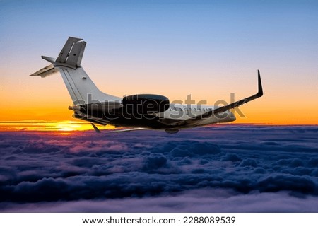Modern private jet flying in the sunrise sky Royalty-Free Stock Photo #2288089539