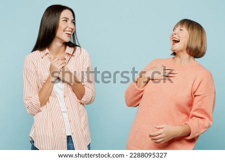Laughing smiling cheerful elder parent mom with young adult daughter two women together wear casual clothes have fun joking tell anecdotes isolated on plain blue cyan background. Family day concept Royalty-Free Stock Photo #2288095327