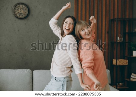 Two cheerful fun cool happy joyful adult women mature mom young kid wearing casual clothes dance near gray sofa couch stay at home flat rest relax spend free spare time in living room. Family concept Royalty-Free Stock Photo #2288095335