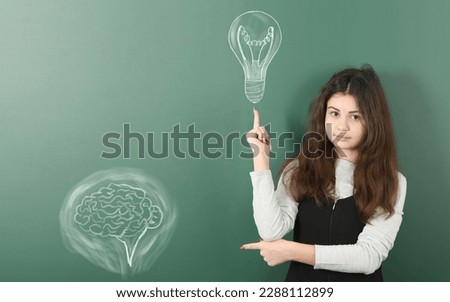 Pre-adolescent girl who just came up with gread idea, isolated school board background with drawn chalk  lighting bulb. High resolution photo. Full depth of field. Royalty-Free Stock Photo #2288112899