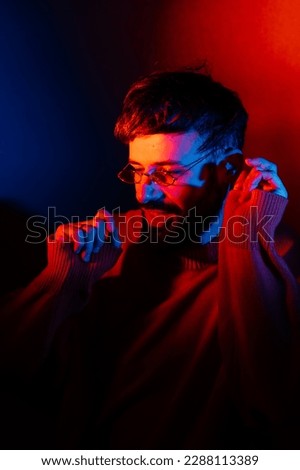 stylized portrait of a man with a beard and black modern glasses using 2 sources of colored light Royalty-Free Stock Photo #2288113389