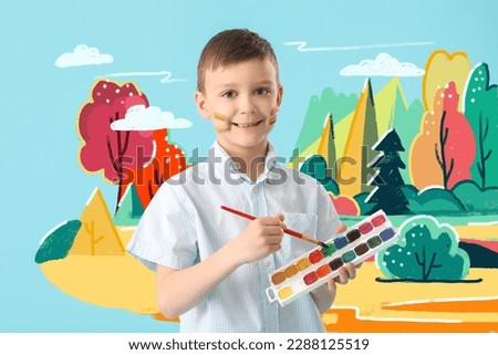Cute little boy painting picture on light blue wall