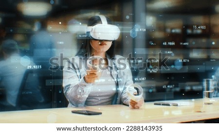 Female office worker uses VR headset and wireless controllers, watches data and numbers in 3D virtual reality. Asian woman works in modern hi-tech IT company. Future innovative digital technologies. Royalty-Free Stock Photo #2288143935