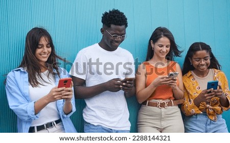 Group of diverse young people using mobile phone outdoor. Friends having fun surfing on social media apps. Youth technology addicted. University students isolated in blue background. Royalty-Free Stock Photo #2288144321