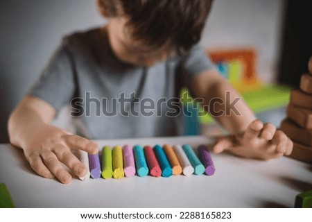 A little boy of three years sits at a table with colored crayons and plasticine lowered his head and cries. The kid is upset and stressed. Autism Spectrum Disorder and Adjustment Difficulties Royalty-Free Stock Photo #2288165823