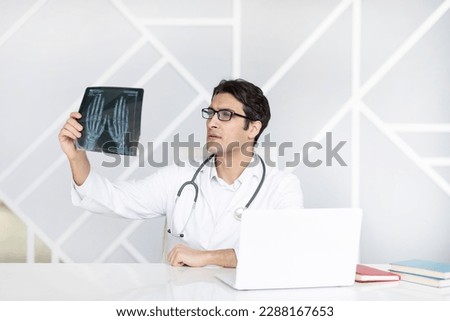 Young male doctor rheumatologist holding x ray image in the office of modern clinic Royalty-Free Stock Photo #2288167653