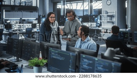 Group of Three Young Indian Software Engineers Use Computer to Discuss a Technological Project in Modern Industrial Office. Group of Male and Female Scientists Work in Research and Development Center Royalty-Free Stock Photo #2288178635