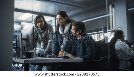 Team of Three Talented Young Software Engineers Use Computer to Discuss a Technological Project in Modern Industrial Office. Group of Male and Female Scientists Work in Research and Development Center Royalty-Free Stock Photo #2288178673