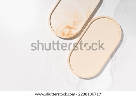 Beauty cosmetics product presentation flat lay mockup scene with beige oval shapes on white marble table with copy space. Trendy sunlight,  top view. Studio photography.