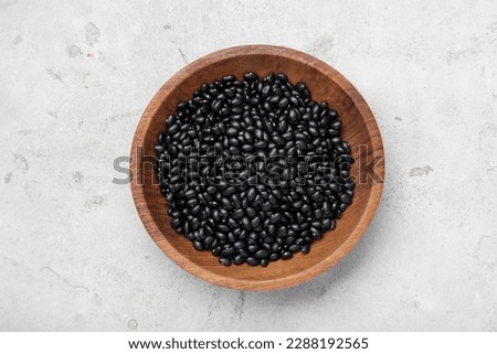 Bowl of raw black beans on light grey table, top view