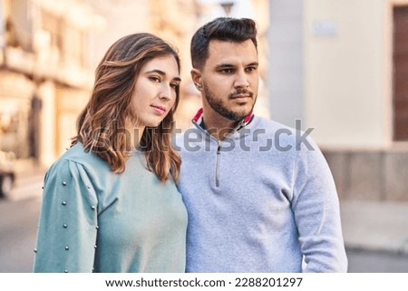 Man and woman hugging each other standing with relaxed expression at street