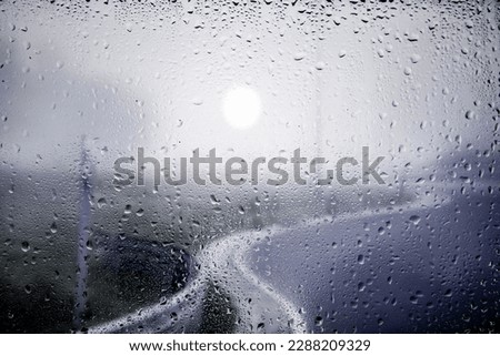 View of the city street in the morning mist through the glass of a window covered with raindrops. Focus on the raindrops.