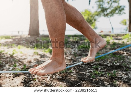 Male feet on the slackline during slacklining in city park Royalty-Free Stock Photo #2288216613