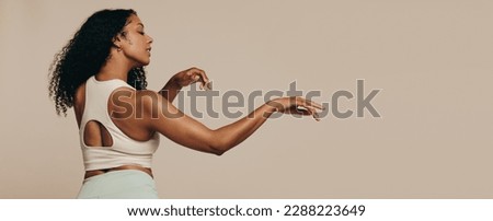 Fit woman dancing in a studio, moving her body effortlessly in fitness clothing. Woman with a lean body sculpture expressing confidence and self-assurance as she finds her flow in her body movement. Royalty-Free Stock Photo #2288223649
