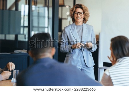 Mature business woman having a discussion with her team. Woman leading a meeting in an office. Business woman presenting her ideas in an office. Group of professionals planning a project. Royalty-Free Stock Photo #2288223665