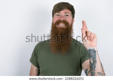 Red haired man wearing printed shirt over white studio background pointing up with fingers number ten in Chinese sign language Shi