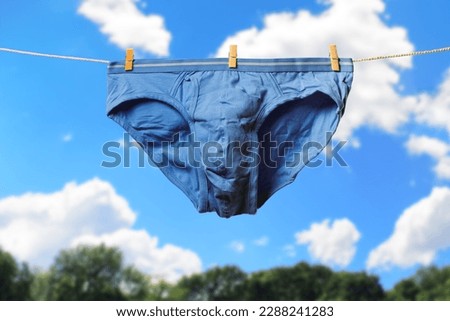 Clean blue men's briefs hanging on rope to dry outdoors on sunny summer day. Clothesline with washed underwear. Regular laundry. Hygiene and clothes care concept Royalty-Free Stock Photo #2288241283