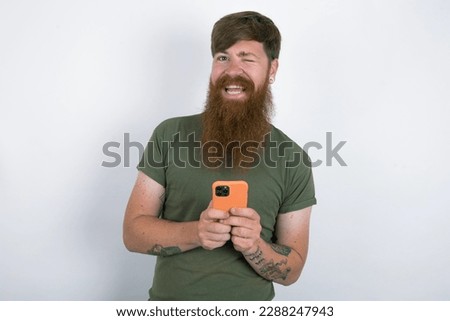 Red haired man wearing green  T-shirt over white studio background taking a selfie  celebrating success