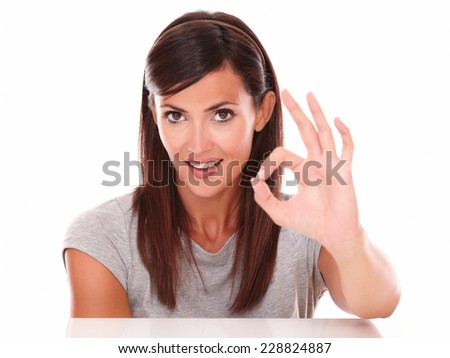 Headshot portrait of cute female with ok sign looking at camera on isolated studio