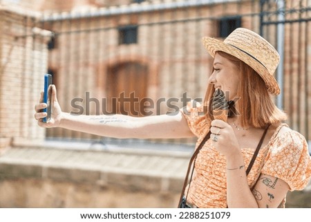 Young redhead woman tourist make selfie by smartphone eating ice cream at street
