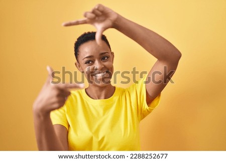 African american woman smiling confident doing photo gesture with hands over isolated yellow background