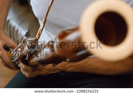 closeup of unrecognizable latino man playing bassoon at home, focus on neck, mouthpiece, music concept, copy space. Royalty-Free Stock Photo #2288256231