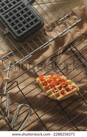 Sweet Croissant Waffle with strawberry sauce and peanuts topping, Sweet Croffle served on a black cooling rack. Homemade croffle