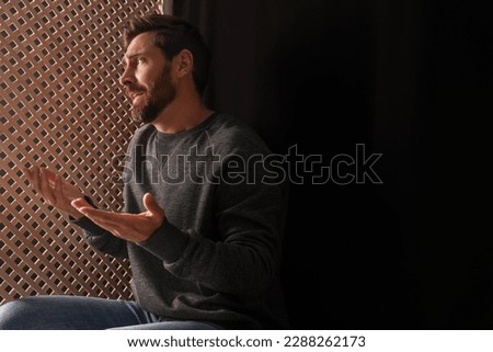 Upset man talking to priest during confession in booth, space for text Royalty-Free Stock Photo #2288262173