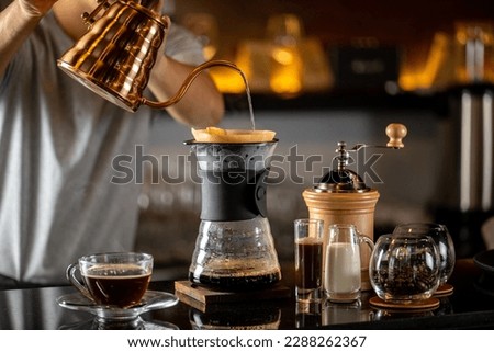 drip coffee, Barista making drip coffee by pouring spills hot water on coffee ground with prepare filter from copper pot to glass transparent chrome drip maker on wooden table in cafe shop Royalty-Free Stock Photo #2288262367