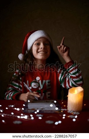 girl writes a letter to Santa in a New Year's hat, New Year's mood, lights